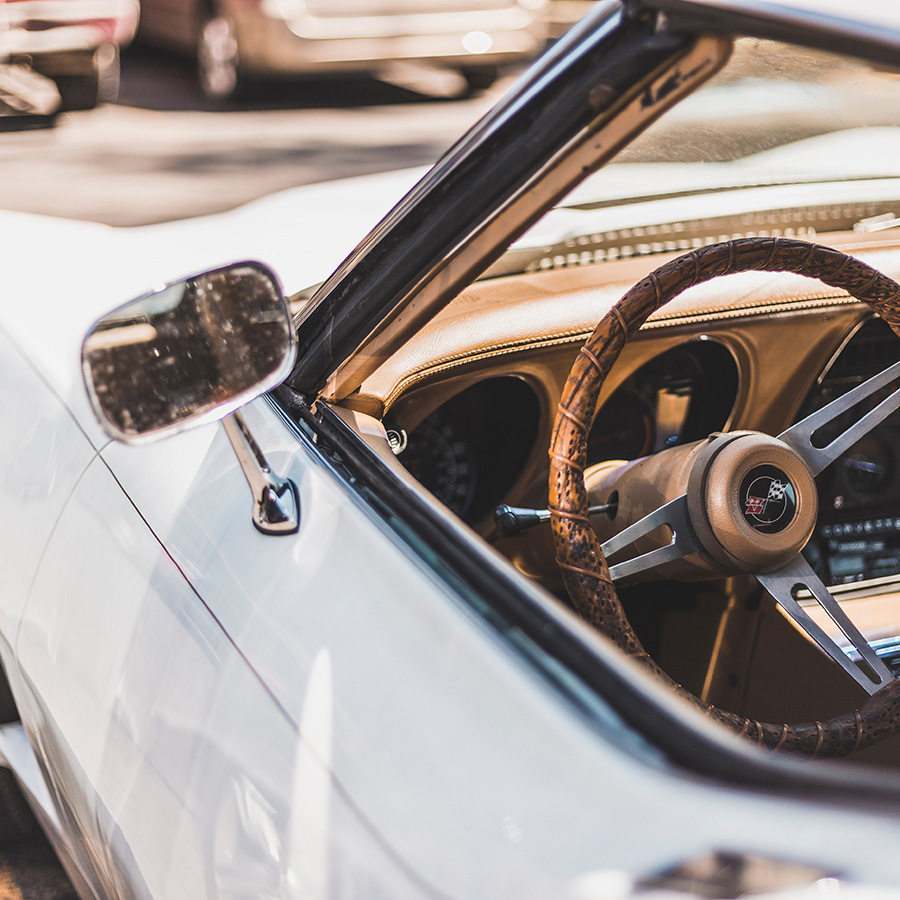 Classic white Corvette Stingray with leather wrapped steering wheel and tan interior.