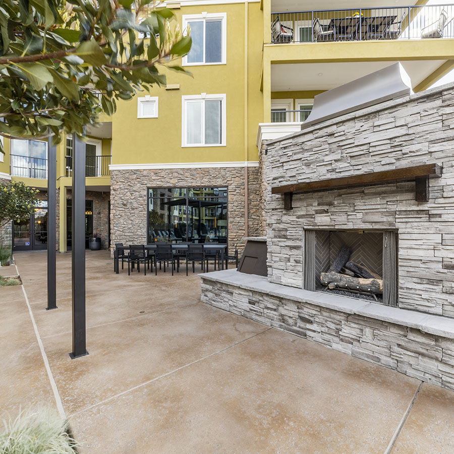 Outdoor lounge with brick fireplace and dining tables.